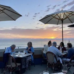 a group of people sitting at tables with umbrellas