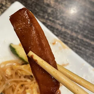 chopsticks holding a piece of meat