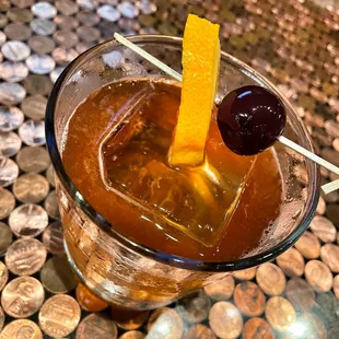 a drink in a glass with an orange garnish