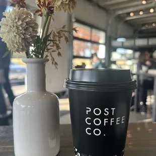 a cup of coffee and a vase of flowers