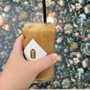 a hand holding a glass of iced coffee