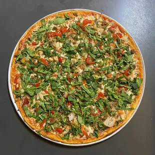 a pizza topped with spinach and tomatoes