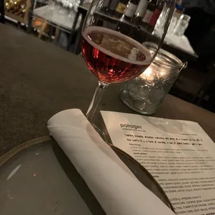 a glass of wine and a menu on a table