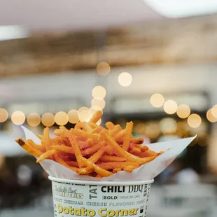 a hand holding a container of fries