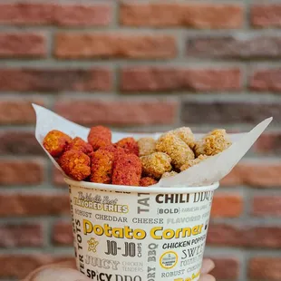 a person holding a paper cup of food