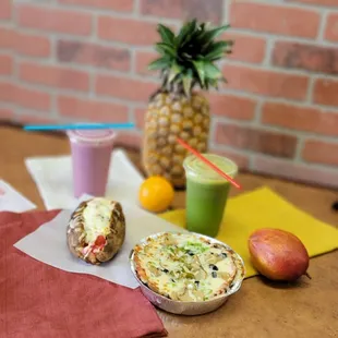 a pineapple, a fruit smoothie, and a baked potato on a table