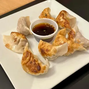 a plate of dumplings with dipping sauce