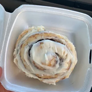 a cinnamon roll in a styrofoam container