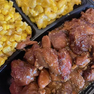 a plate of meat, corn and macaroni