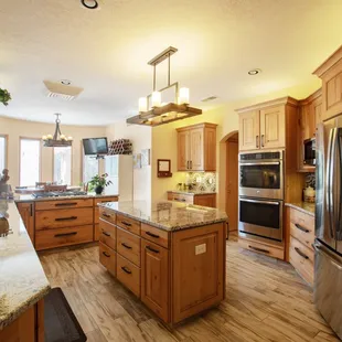 Wide angle view of kitchen with granite countertops, and wood-look porcelain tile.