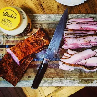 a wooden cutting board with a knife and some meat on it