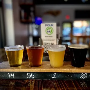 a flight of beers on a wooden tray