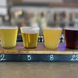 a flight of beers on a wooden board