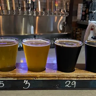 a flight of beers on a wooden tray