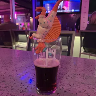 a pint of beer with a paper dragon on top