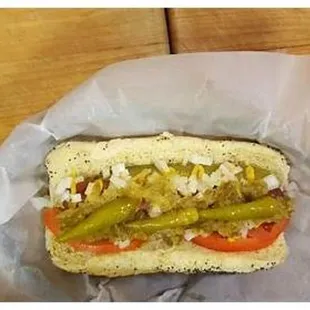 a hot dog with pickles and tomatoes