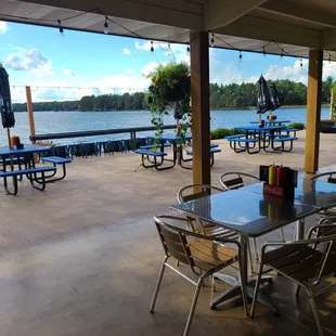tables and chairs on a patio overlooking a lake