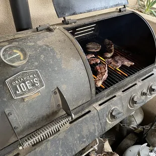 a grill with steaks cooking on it