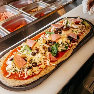 a person putting toppings on a pizza