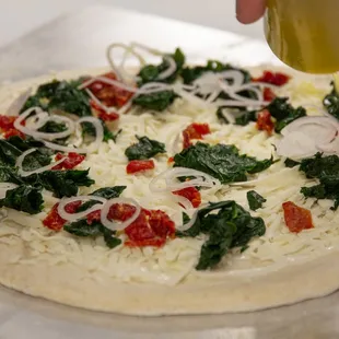 a person putting cheese on a pizza