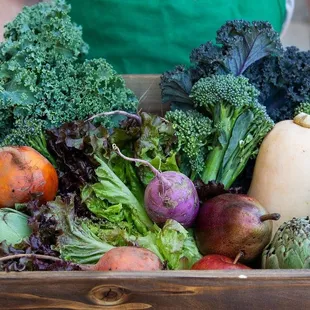 a person holding a box of vegetables
