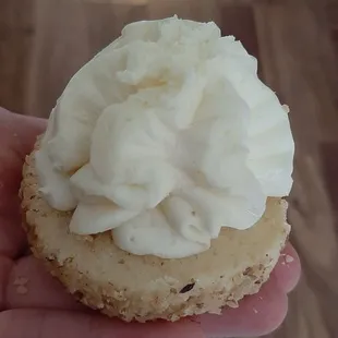 a hand holding a pastry with white frosting