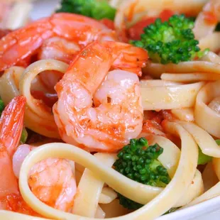 a plate of pasta with shrimp and broccoli