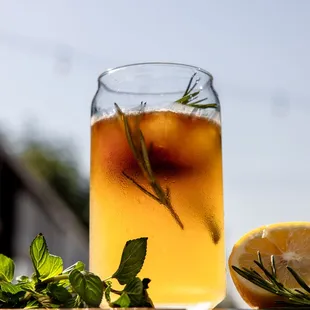 a glass of iced tea with a sprig of rosemary