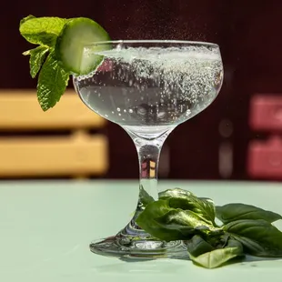 a glass of water with a cucumber garnish