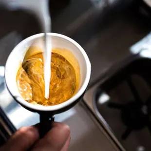 a person pouring coffee into a cup