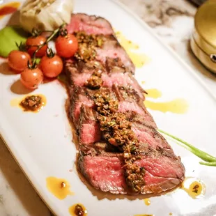 Flank steak with green harissa and hearth roasted tomato.