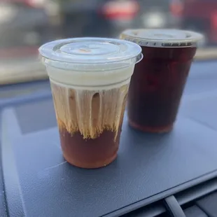 two cups of coffee on the dashboard of a car