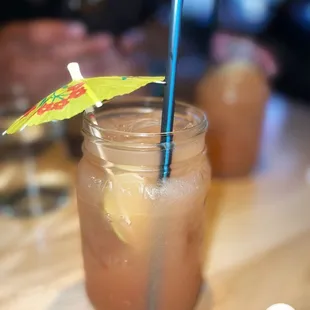 a drink in a mason jar with a paper umbrella