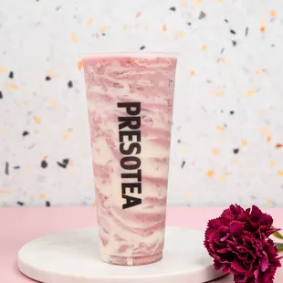 a pink marbled cup with a flower on a white plate