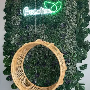 a hanging wicker chair in front of a green wall