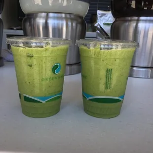 two cups of green smoothie on a counter