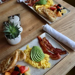 a breakfast of eggs, bacon, fruit, and toast