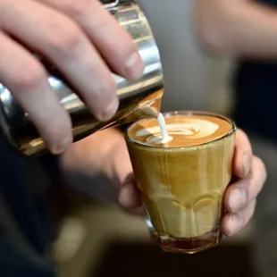 a person pouring coffee into a glass