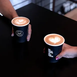 two people holding cups of coffee