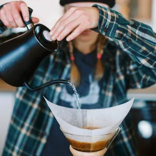 a person pouring water into a coffee pot