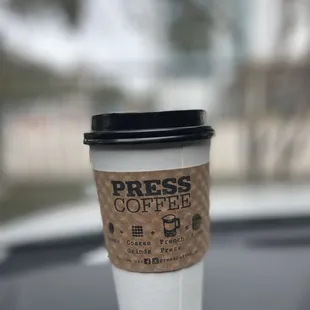 a cup of coffee on the dashboard of a car