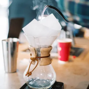 a glass coffee maker with a wooden handle