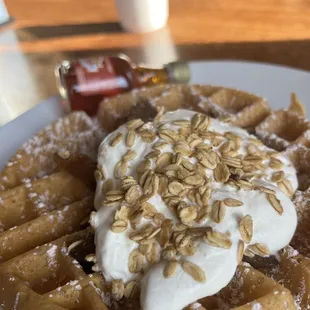 a waffle topped with whipped cream and oats
