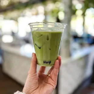 a hand holding a cup of matcha