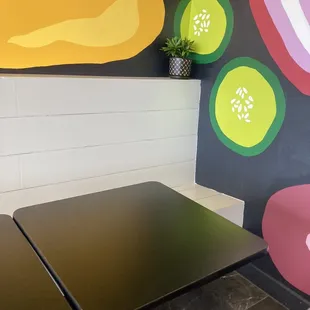 Cute seating section with 4 tables, chairs, and a colorful mural.