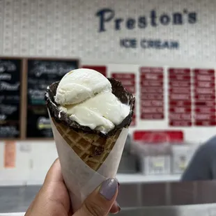 a hand holding a cone of ice cream