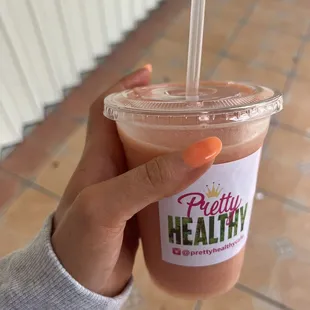 a hand holding a cup of smoothie