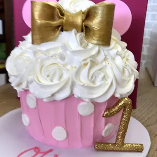 a cupcake with white frosting and a gold bow