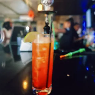 a cocktail on a bar with people in the background