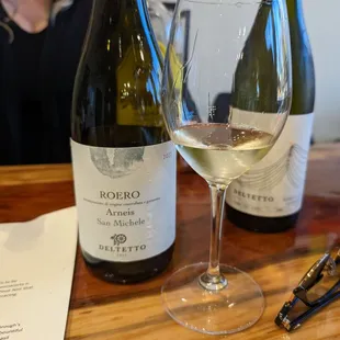 two bottles of wine and a glass of wine